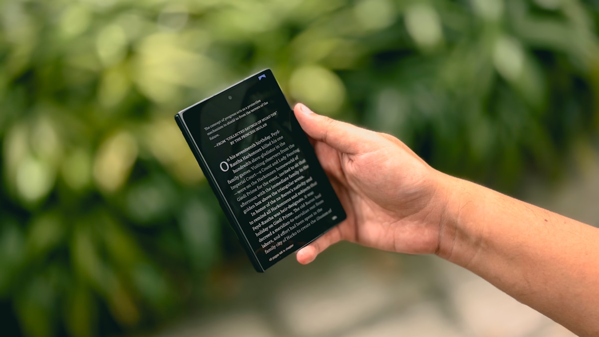 Mobile reading device held against a green natural background