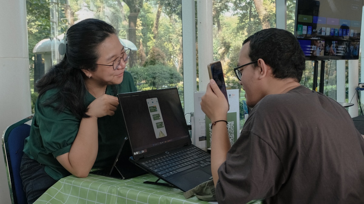 People testing a mobile application beside a laptop