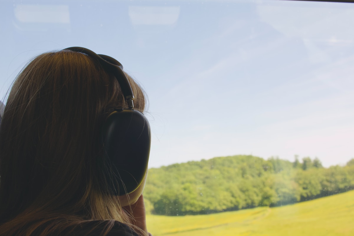 Person wearing headphones while looking across a natural landscape