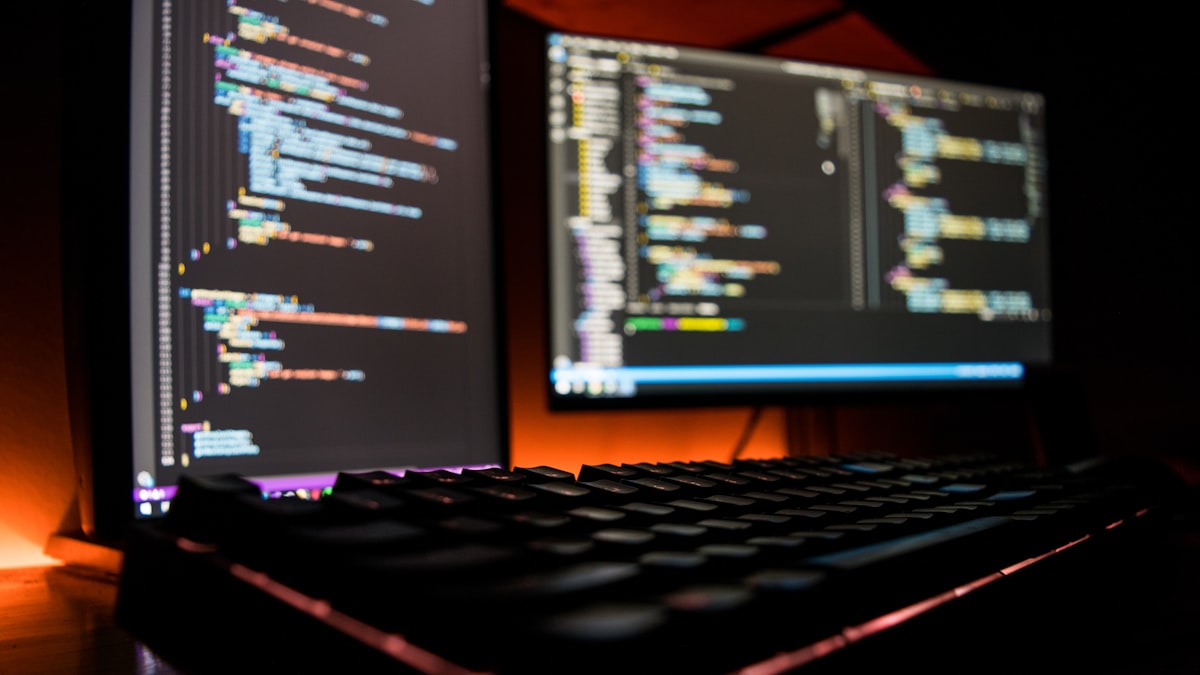 A developer workstation at night with source code across two monitors