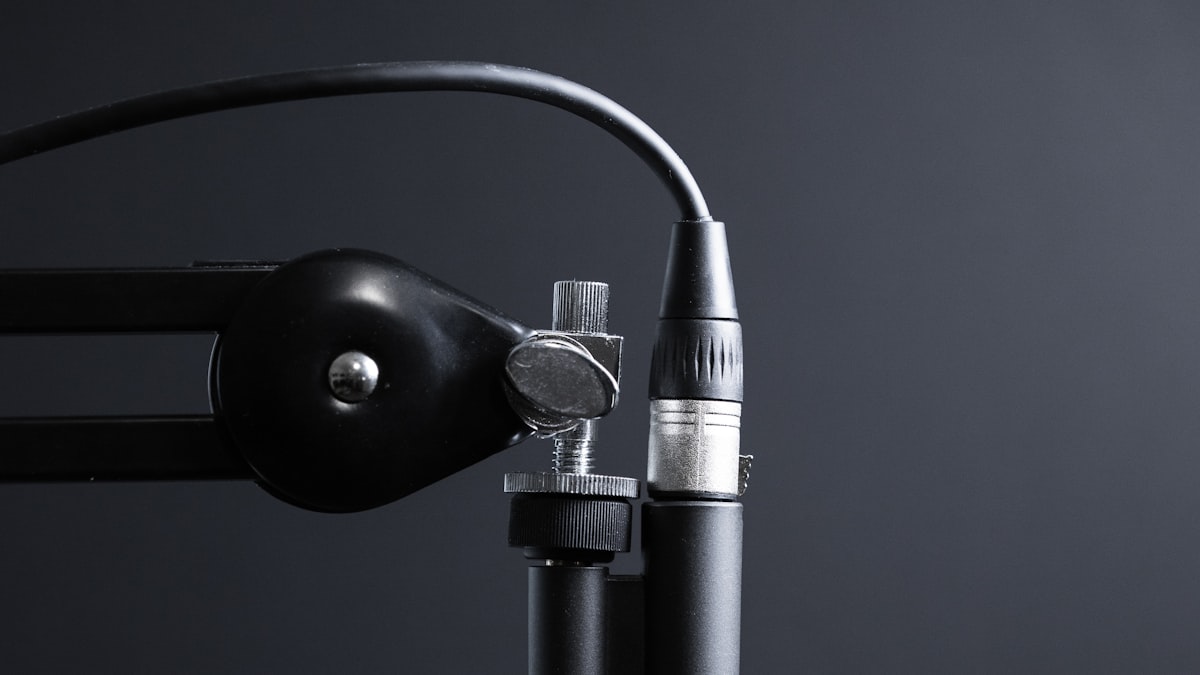 A studio microphone on a boom arm against a dark background