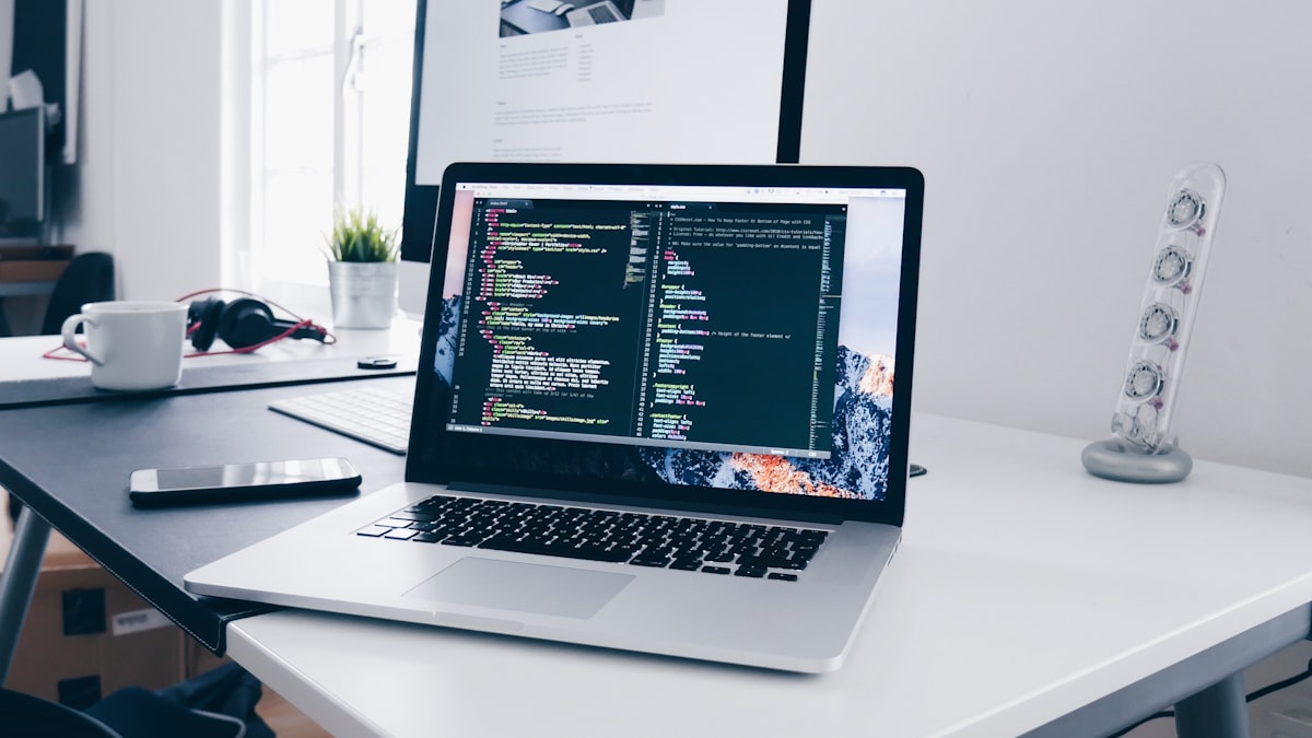 A laptop on a clean desk with code open on screen