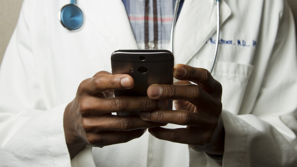 A clinician in a white coat using a phone