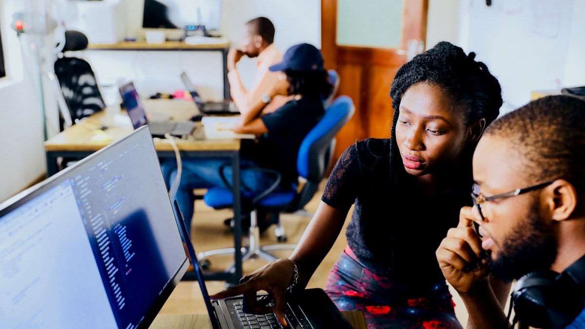 Two colleagues reviewing work together at a screen in an open-plan office