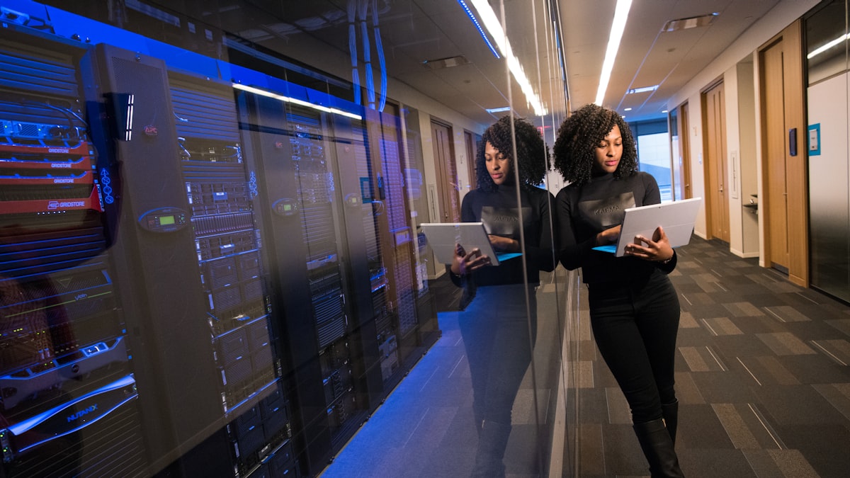 Two engineers walking a data centre aisle with laptops open