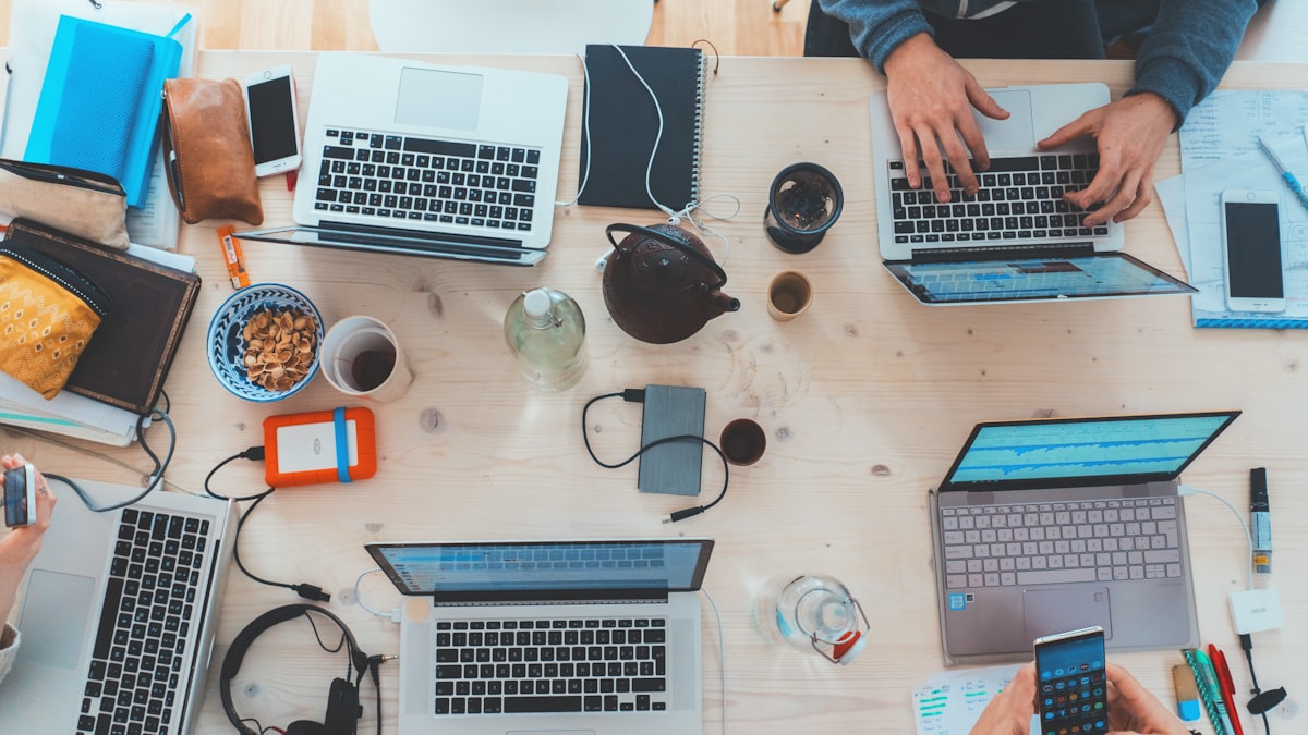 An overhead view of a desk covered with laptops, phones and tablets
