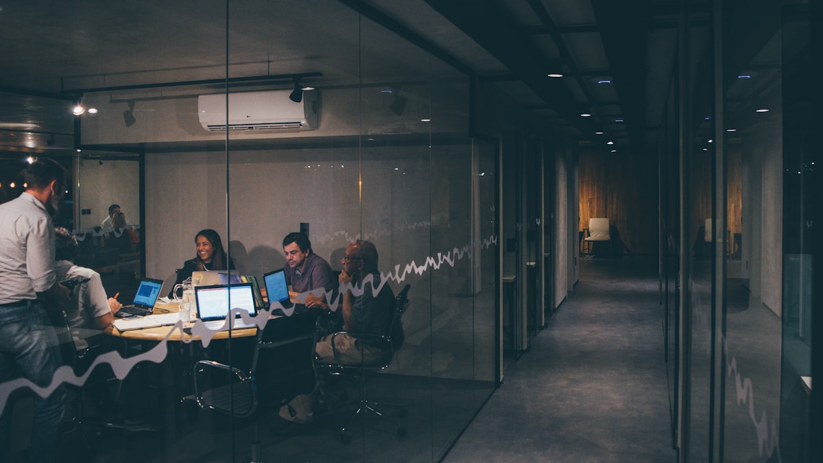 A team working late in a glass-walled meeting room