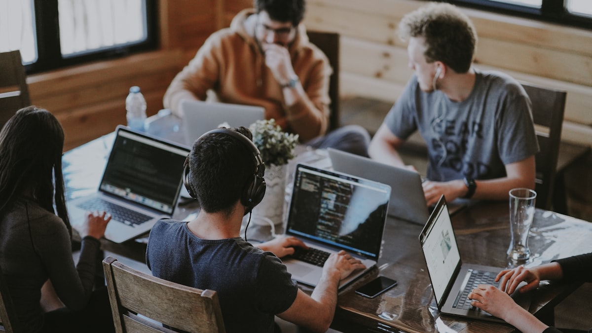 A distributed team working together on laptops around a low table